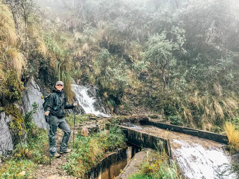 Me wearing rain gear next to waterfall on the Salkantay trek to Machu Picchu.