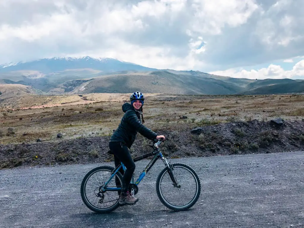 Me on a bike in front of a cloud covered Cotopaxi on my Cotopaxi day trip