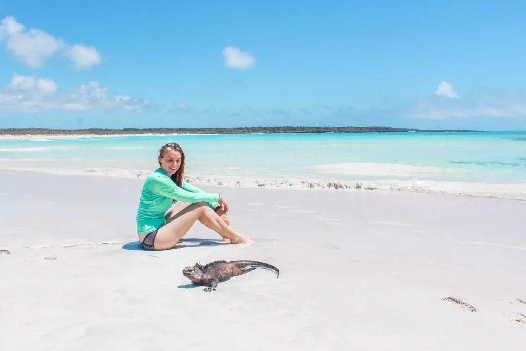 Sitting on a white sand beach with a marine iguana in the Galapagos Islands.