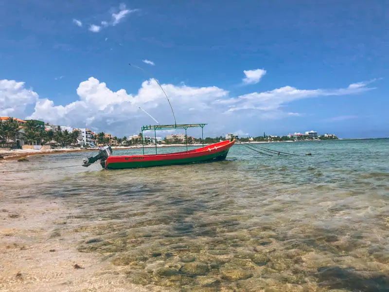 Lunch view of a boat and crystal clear water at La Buena Vida in Akumal, Mexico