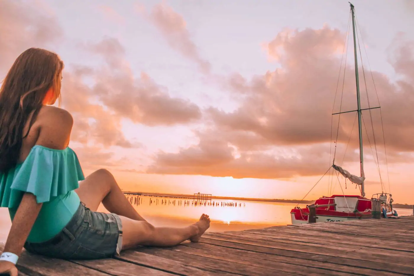 Sitting on the pier watching a bright orange sunrise over Laguna Bacalar in the Yucatan Peninsula in Mexico.