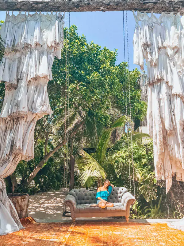In Tulum Mexico, visit Casa Malca and sit on the large couch swing at the entrance of the hotel. 