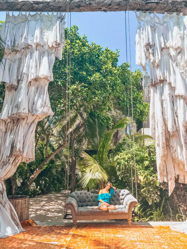In Tulum Mexico, visit Casa Malca and sit on the large couch swing at the entrance of the hotel.