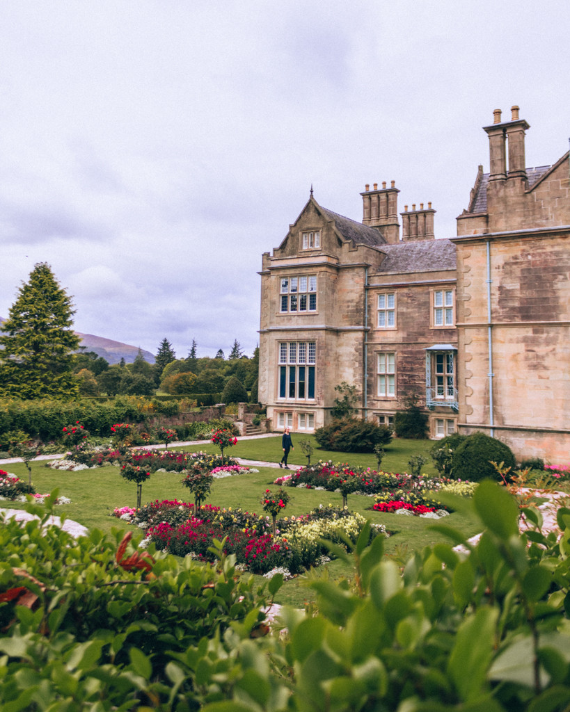 Muckross House and its gardens in Killarney National Park surrounded by green landscape.