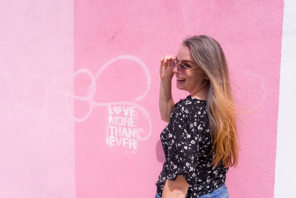 Girl in front of pink wall that says Love more than Ever