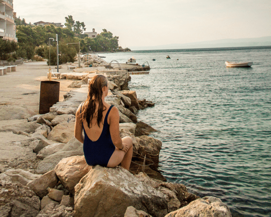 girl sitting on rocks overlooking the sea 