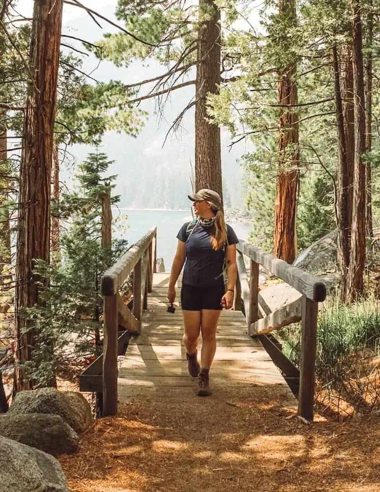 Hiking through the forest across a bridge on the Rubicon Trail with Lake Tahoe in the background carrying my day hike essentials.