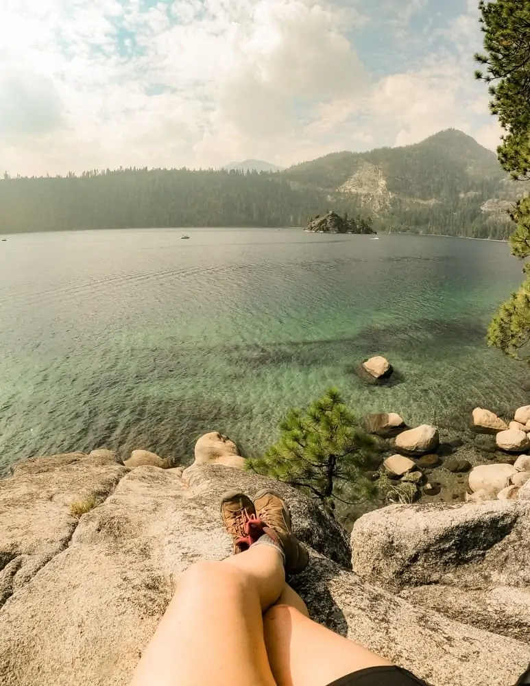 My feet in hiking boots sitting on a boulder looking at Emerald Bay
