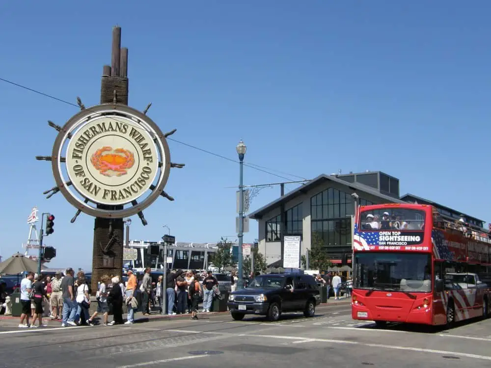 Fisherman's Wharf San Francisco sign with red tour bus.