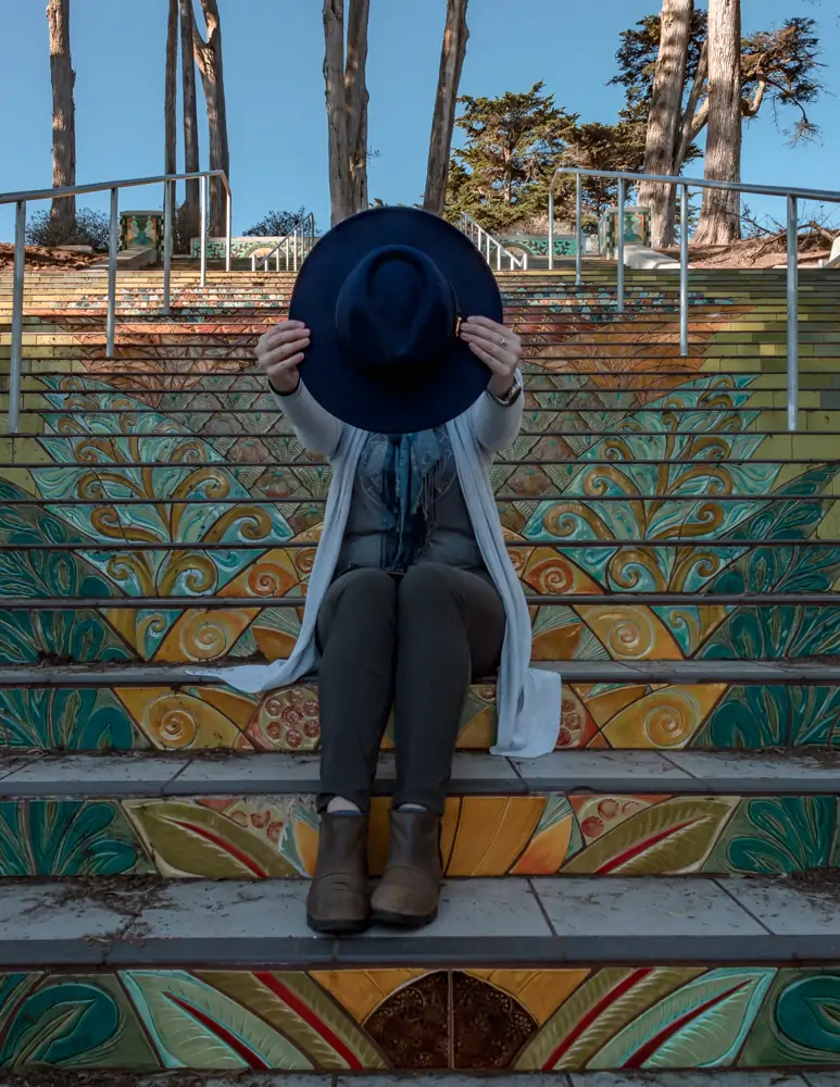 Me holding hat in front of my face on the Lincoln St. Steps