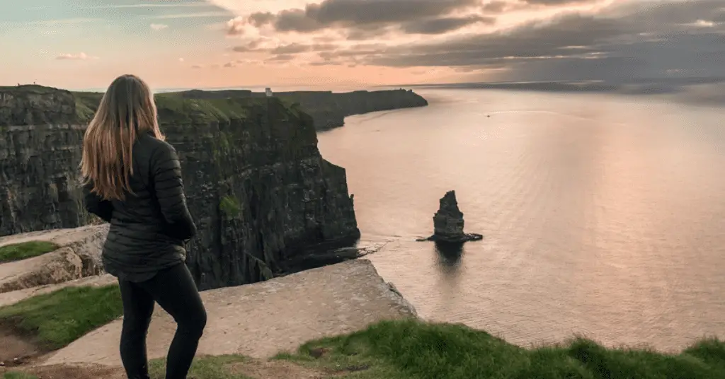 Planning a solo trip? Here's how to decide your destination. Image: Woman overlooking the Cliffs of Moher in Ireland