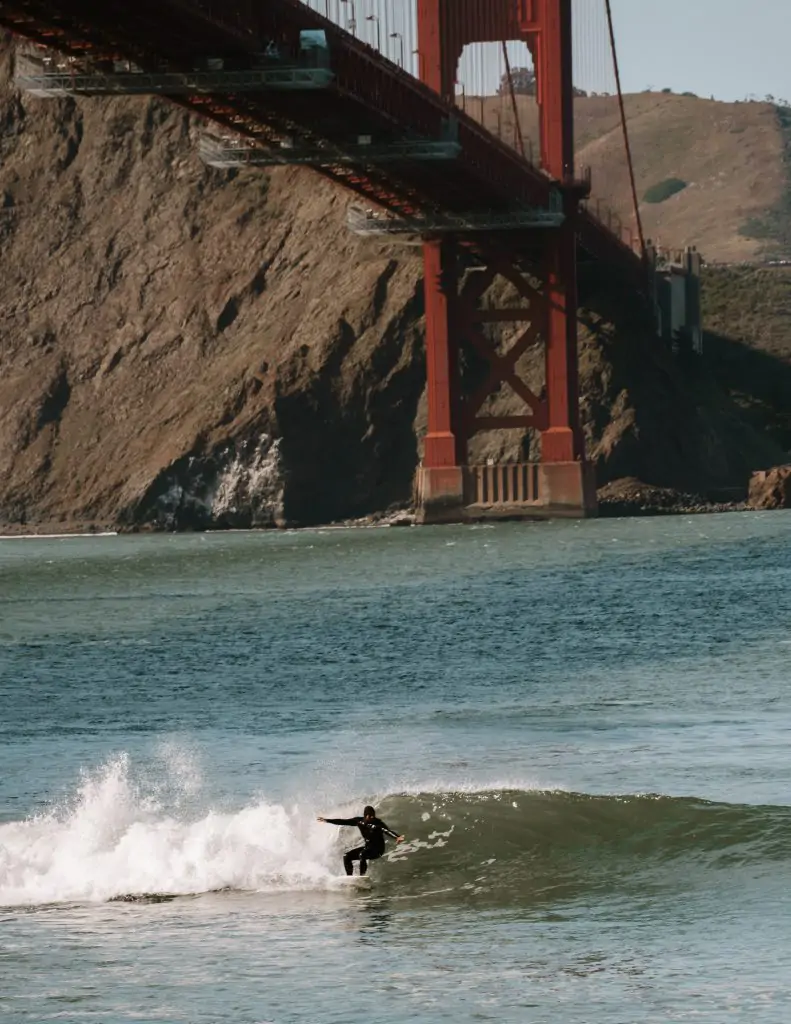 Surfer underneath the Golden Gate Bridge at Fort Point, San Francisco