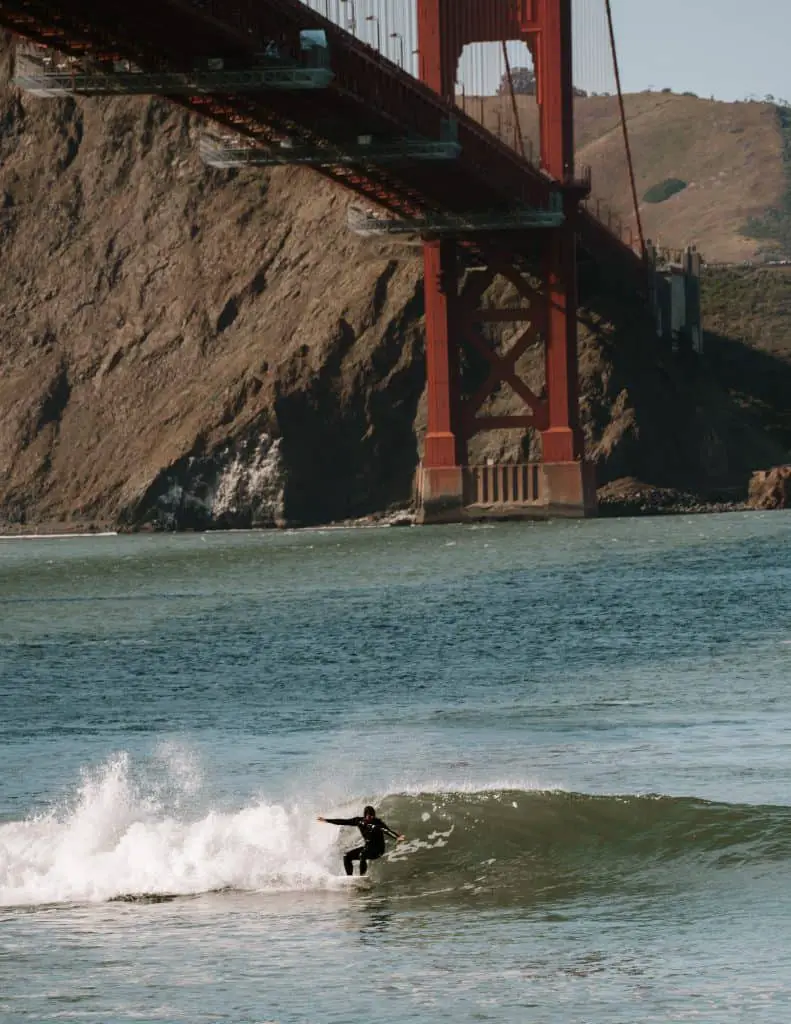 Surfer underneath the Golden Gate Bridge at Fort Point, San Francisco.