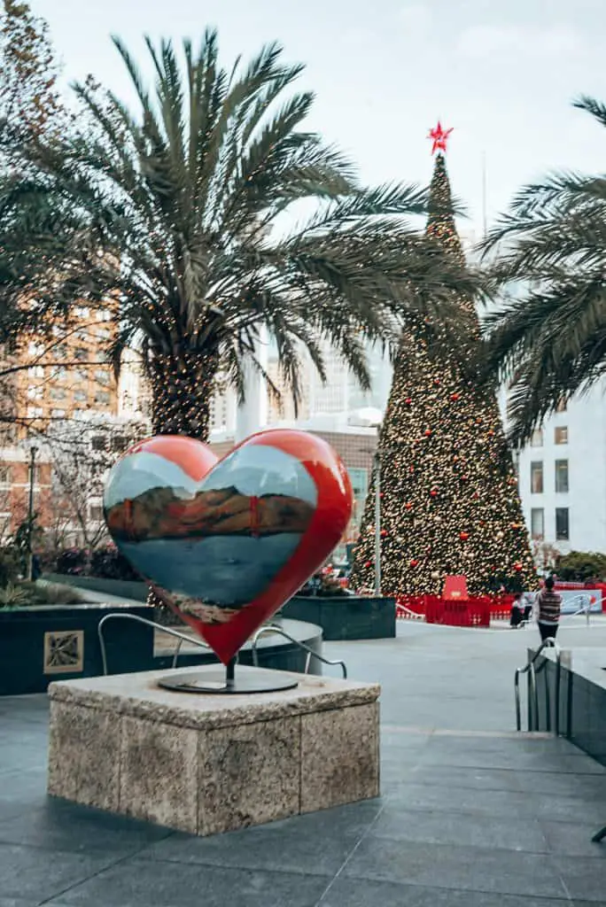 Christmas tree lit up in Union Square with a heart sculpture in front of Macy's during Christmas in San Francisco, California.