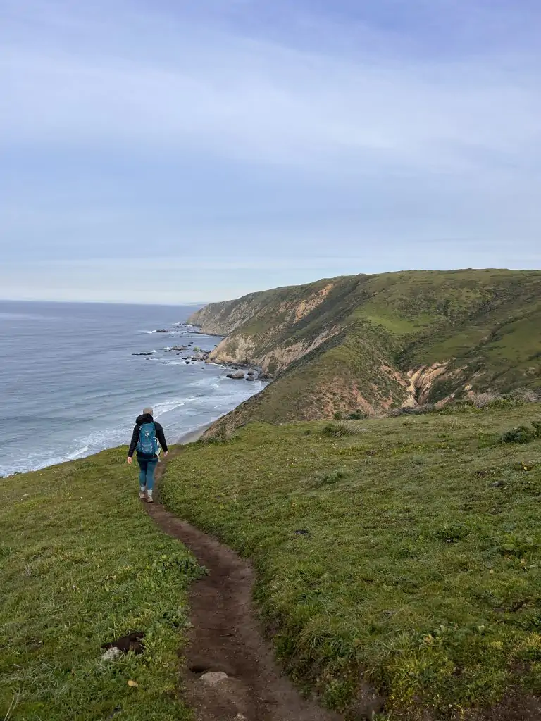 Me walking down narrow path on the Tomales Point Trail with the ocean in the distance.