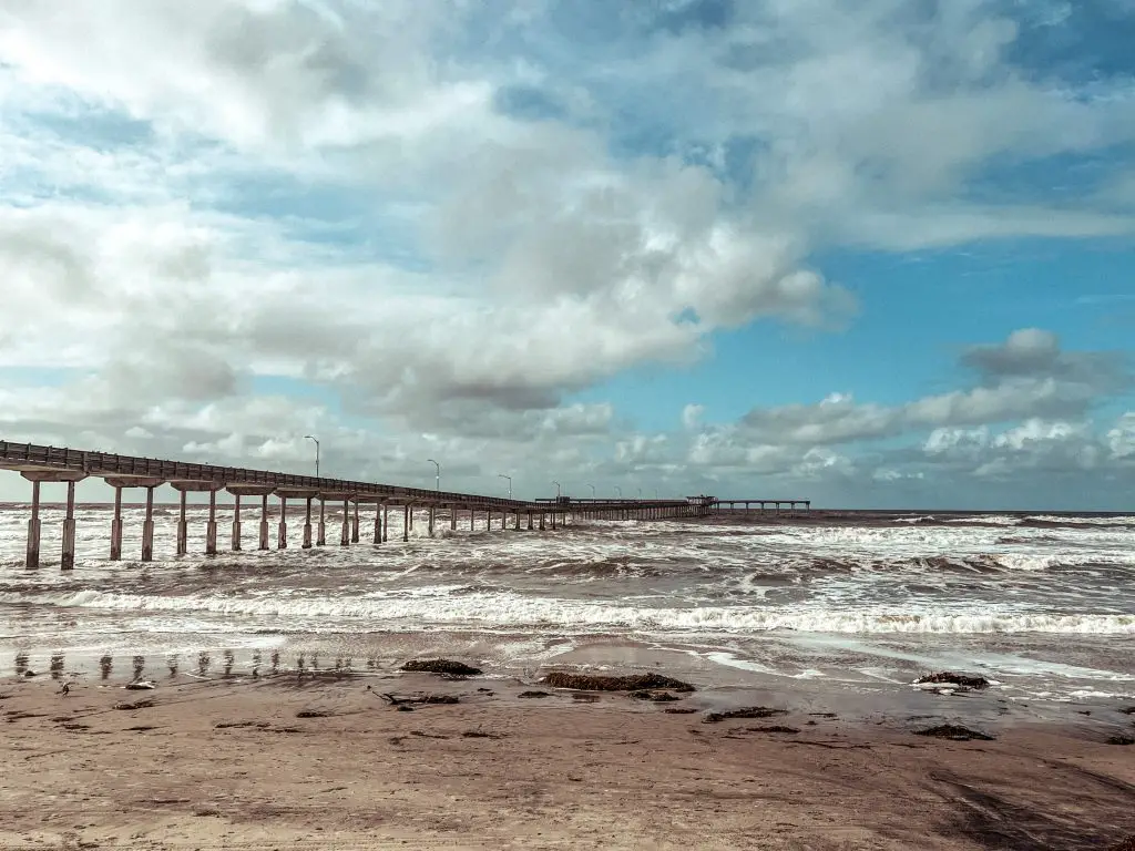 Sandy beach with large pier to the left in Ocean Beach, San Diego.