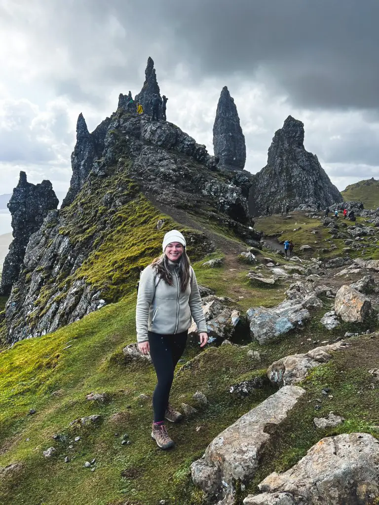 Me wearing a beanie, fleece, black leggings, and hiking shoes while hiking the Old Man of Storr. 