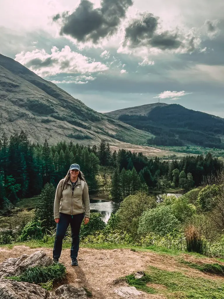 Scotland packing list. Me standing in front of a lake in Glencoe wearing hiking clothes