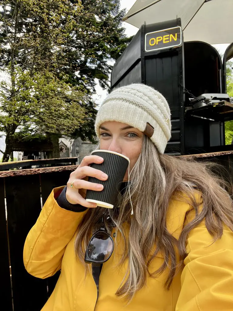 Me drinking tea in front of Glenfinnan Coffee Co in Scotland.