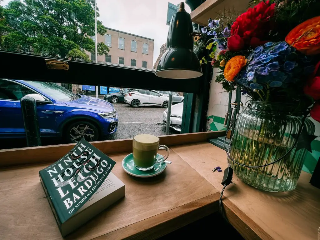Matcha latte and a book on the counter at Cowan and Sons in Edinburgh, Scotland