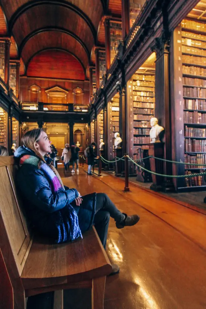 Sitting on a bench in the Long Room of the Trinity College Library.