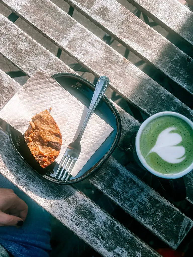 Green matcha latte and a pastry on a slated wood table.