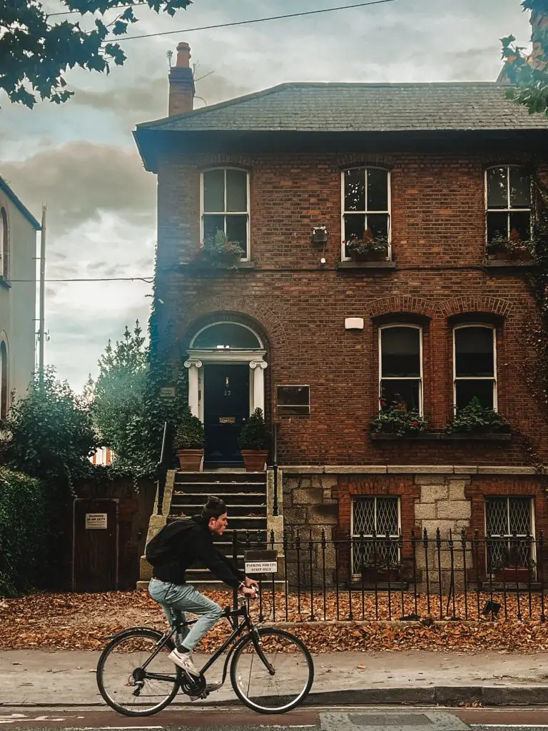 Cyclist rides in front of a home near Merrion Square Park.