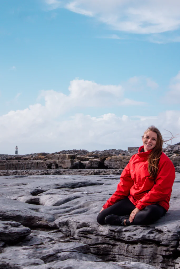 Sitting on the limestone cliffs with the lighthouse in the distance on Inisheer Island of the Aran Islands.