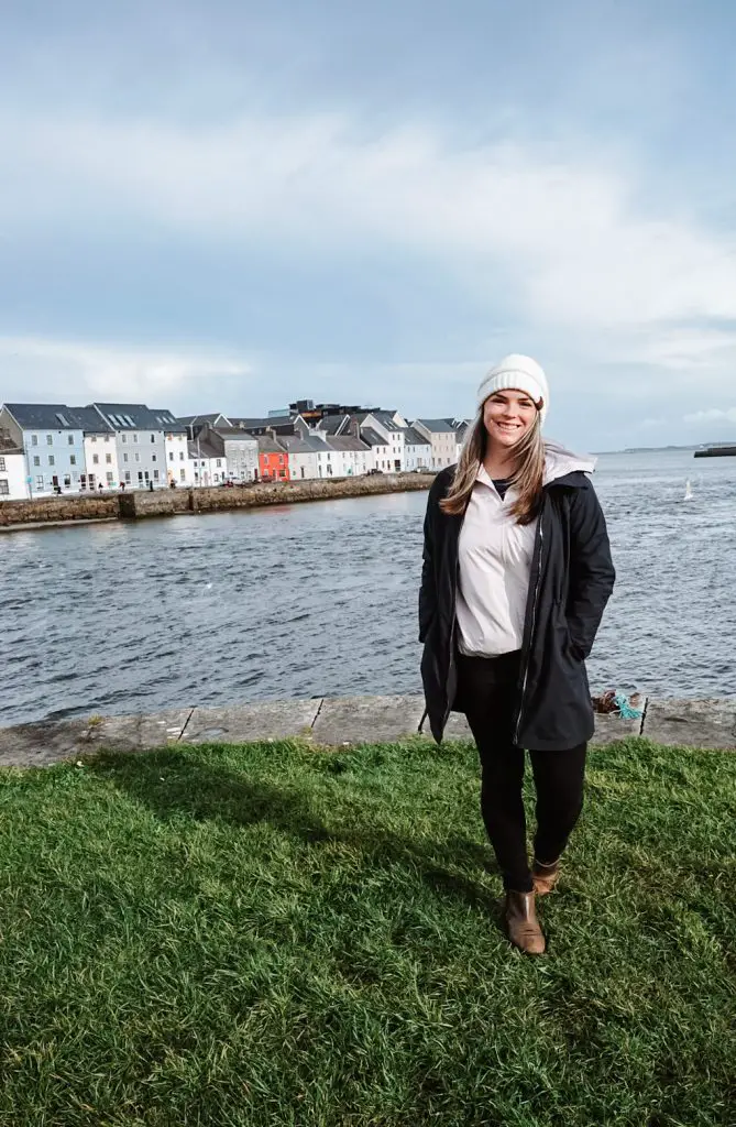 standing on a grassy patch in front of Galway Bay and the colorful houses.