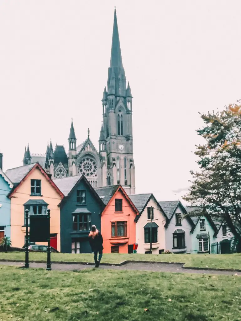 Large gothic church behind colorful homes in Cobh, Cork.