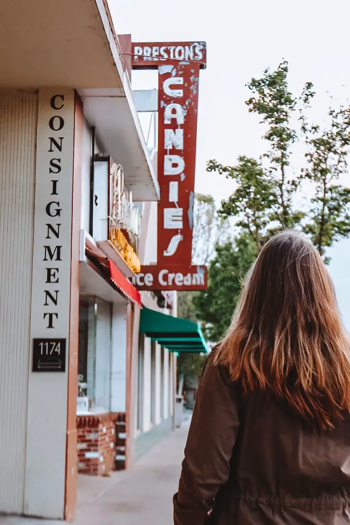 Back of woman looking at Preston's Candy and Ice Cream shop.