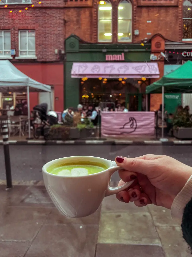 Matcha latte held in front of a Dublin street. 