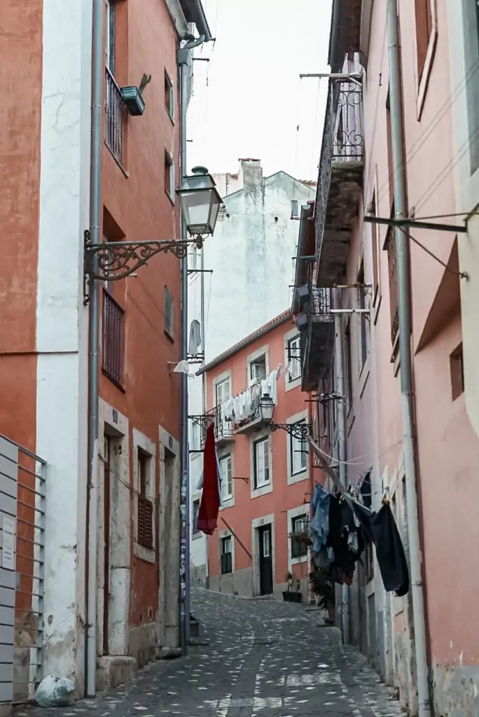 Narrow streets with handing laundry in Alfama neighborhood in Lisbon, Portugal.