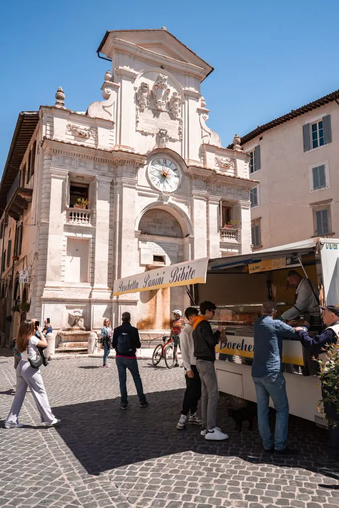 Fountain and porchetta truck in the main square, Piazza del Mercato in Spoleto, Italy.