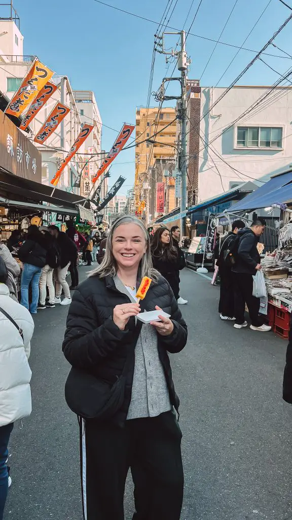 Me eating an egg omelet in Tsukiji Fish Market in Tokyo, Japan.