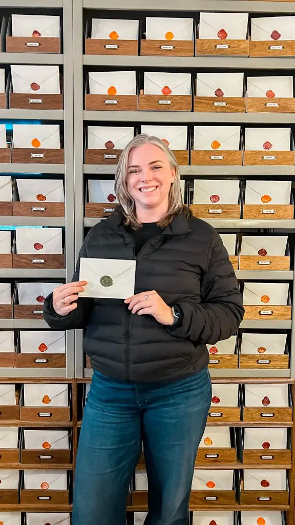 Me holding a letter in front of a wall of letters at Futo Cafe in Tokyo, Japan.