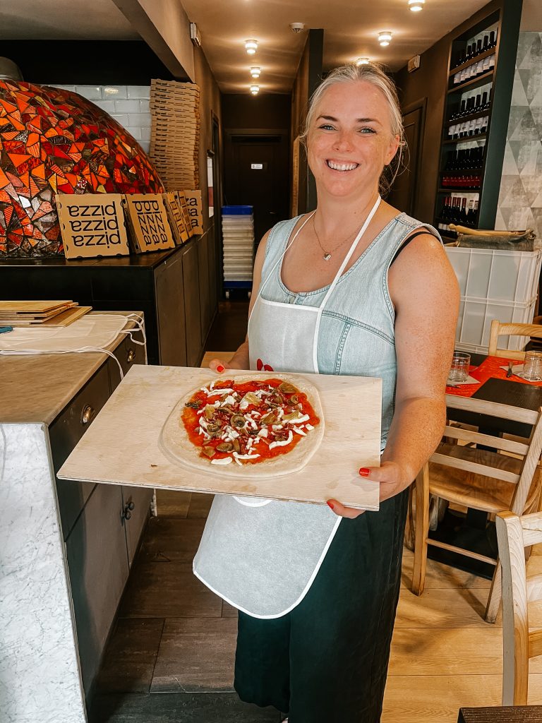 Katie holding a pizza in Rome, Italy.