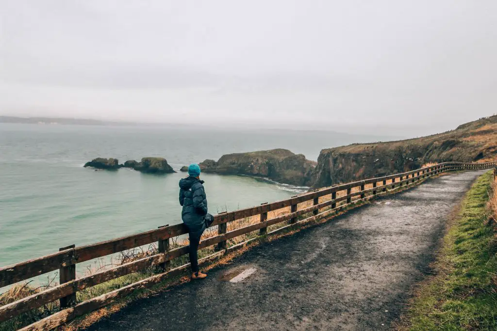 Katie wearing a long puffer jacket on a walking path in Northern Ireland on a stormy day.