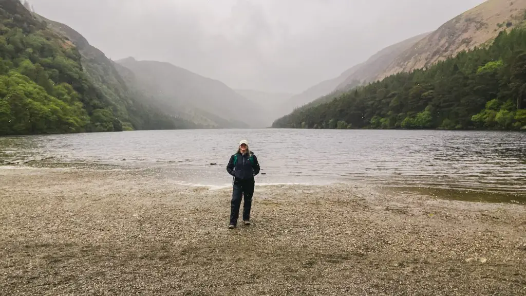 Katie standing in front of the Upper Lake in Glendalough on a rainy day wearing all black.