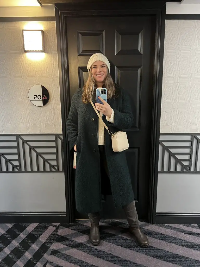 Katie wearing a long wool coat in a Dublin hotel hallway.