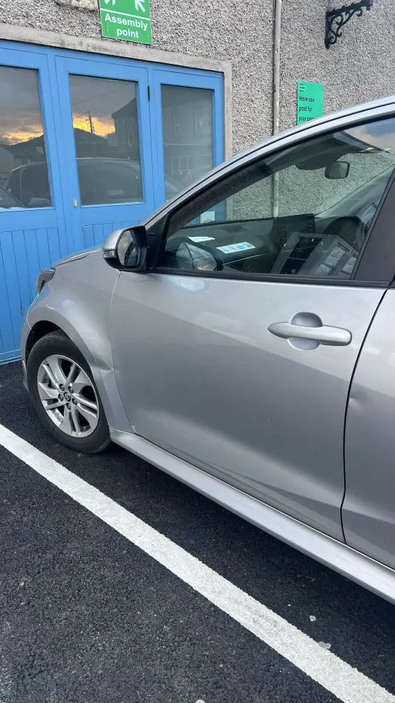 Front half of rental car showing damage around the front left tire.