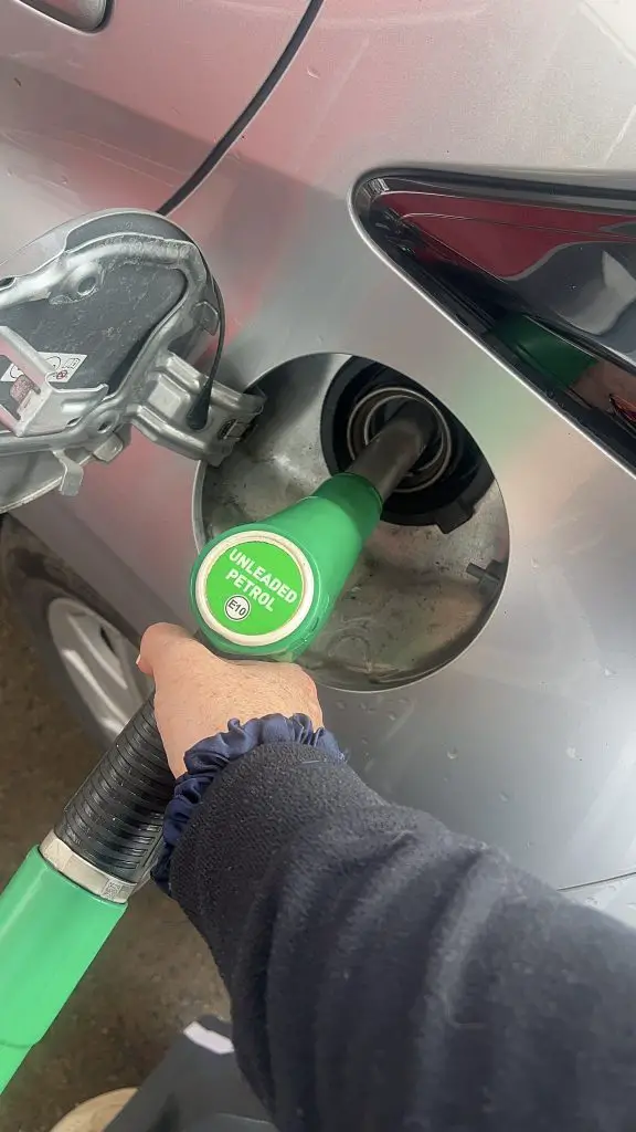 Pumping gas from green gas handle into silver car.