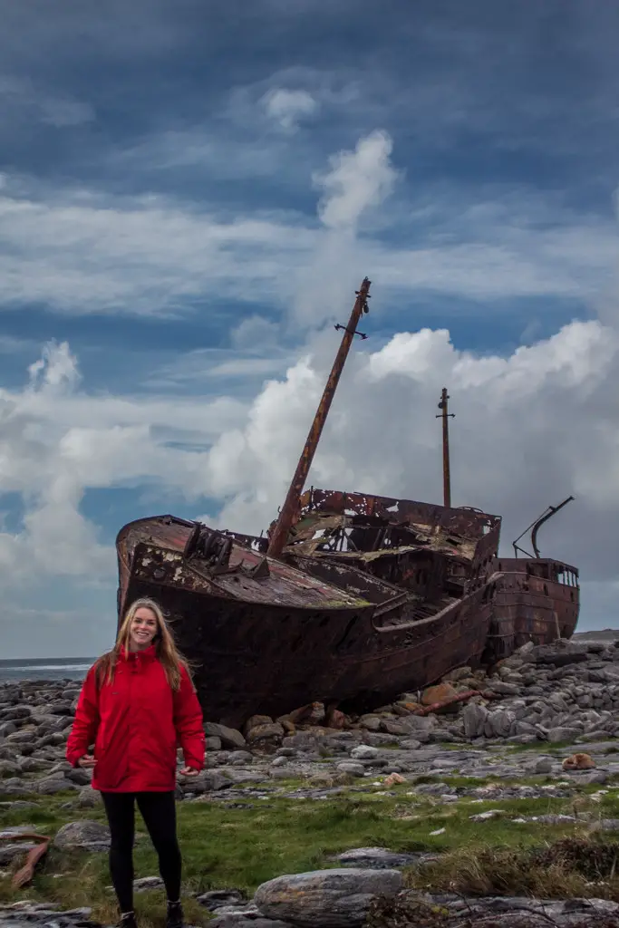 Katie in front of Plassey Shipwreck on the Aran Islands wearing a bright red jacket.