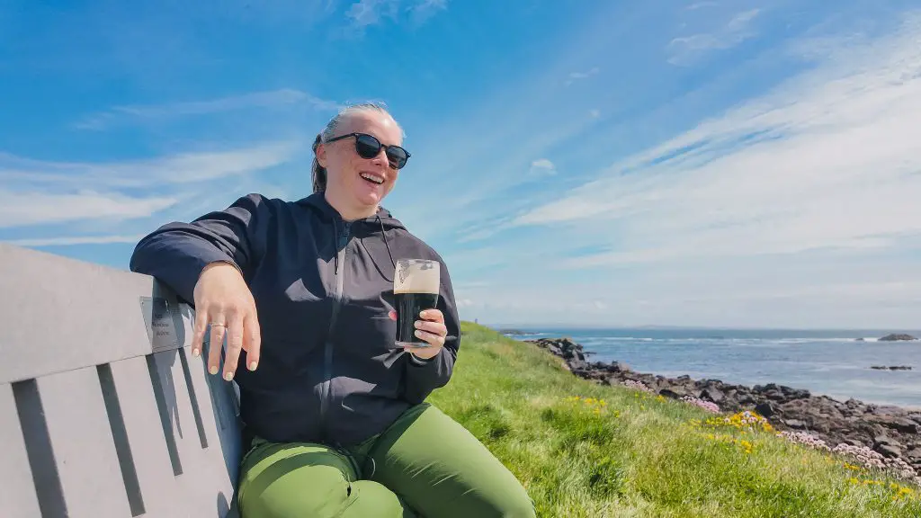 Katie drinking Guinness on a bench on a sunny day on Inishbofin, Ireland.