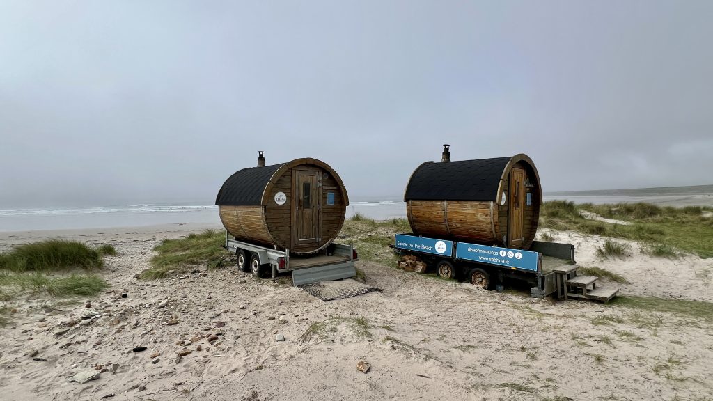 Two barrel saunas on the sand in front of Keel beach on Achill Island, Ireland.