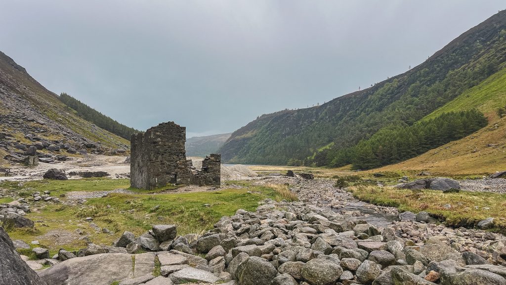 Rocky ruins of a mining village surrounded by rocky ground beneath the mountains in Glendalough, Ireland.