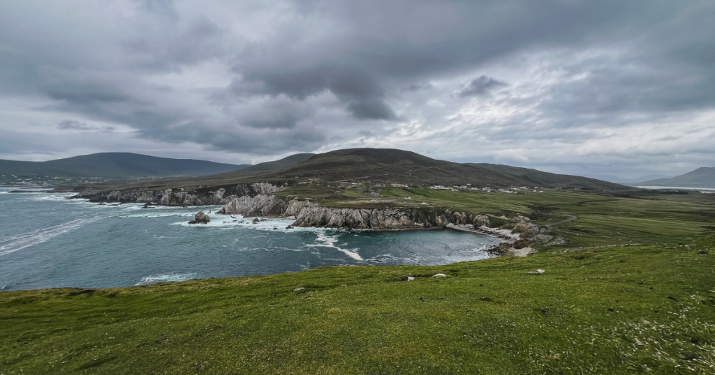 Wide view of green and limestone cliffs under a stormy sky on Achill Island.