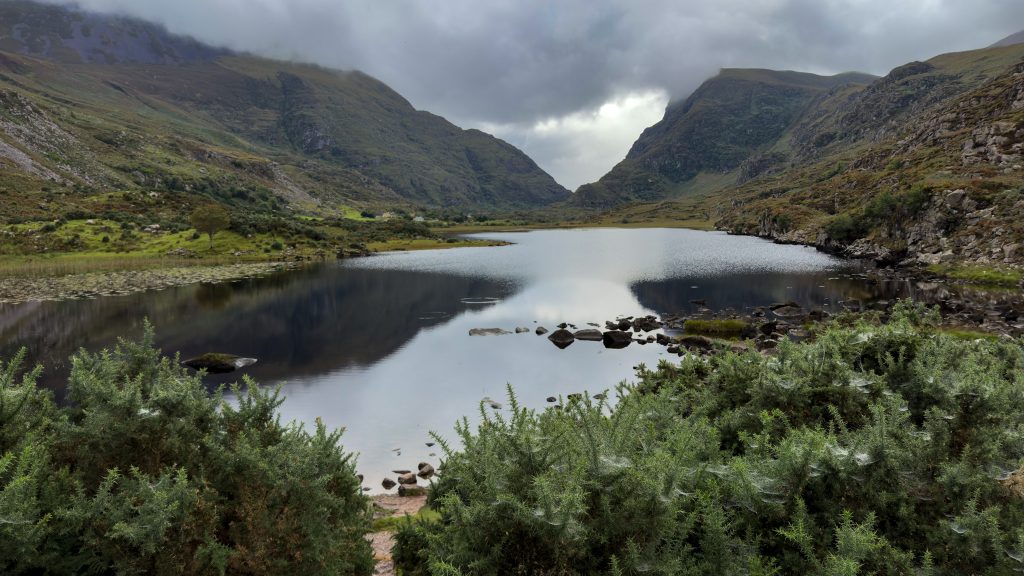 Lake reflects the mountain peaks on a stormy day.