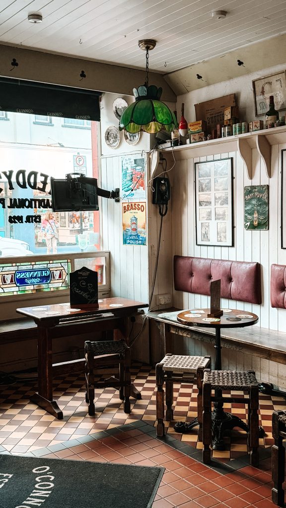 Low brown tables with stools in the corner of a pub next to a window.